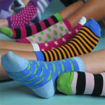 Feet wearing different multi-coloured socks.